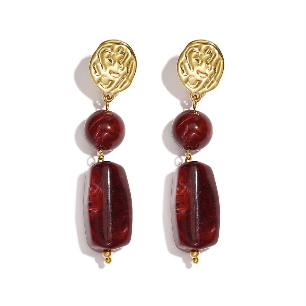 Gold statement drop earrings with deep wine-red round and elongated beads.
