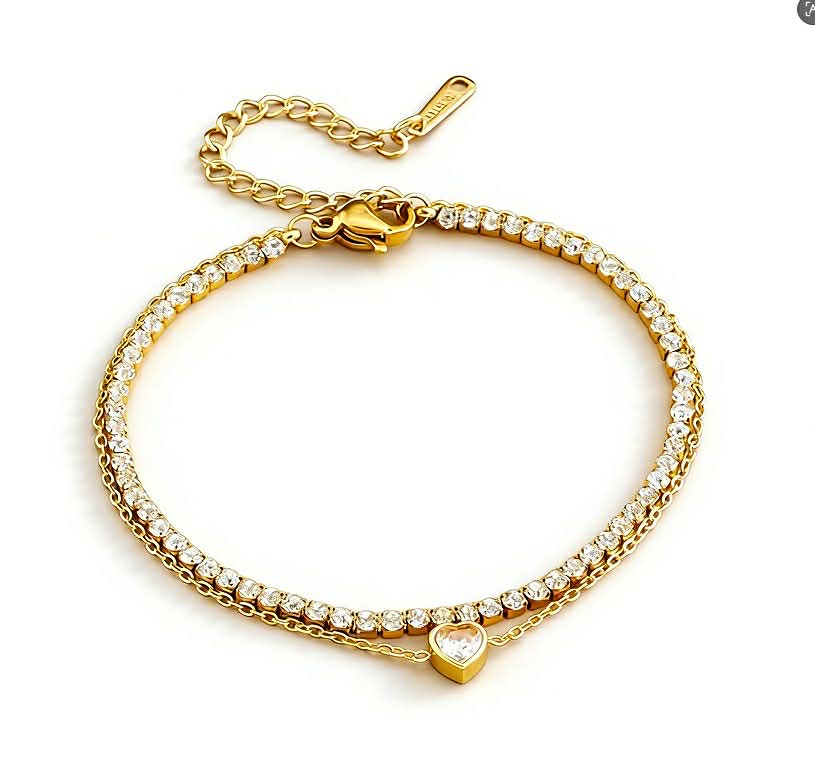 Double layer gold-tone bracelet with thin 2mm tennis chain and delicate second chain featuring a small heart-shaped crystal centerpiece and adjustable clasp